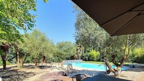 Un espacio al aire libre con piscina, terraza de madera y sillas de descanso.