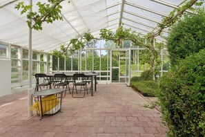 A greenhouse with a table and chairs, surrounded by greenery. - Charming 45 m² house in peaceful setting (Gelsted)