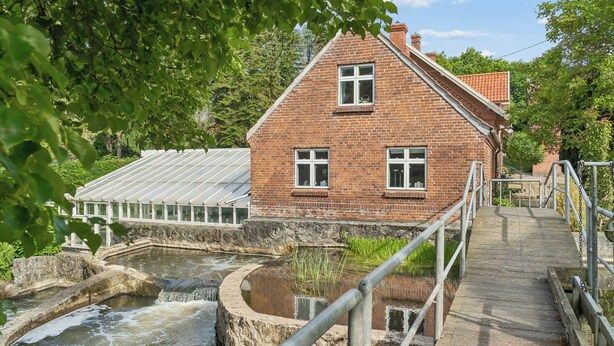 Ein Backsteinhaus mit einer Holzterrasse und einem kleinen Wasserspiel.