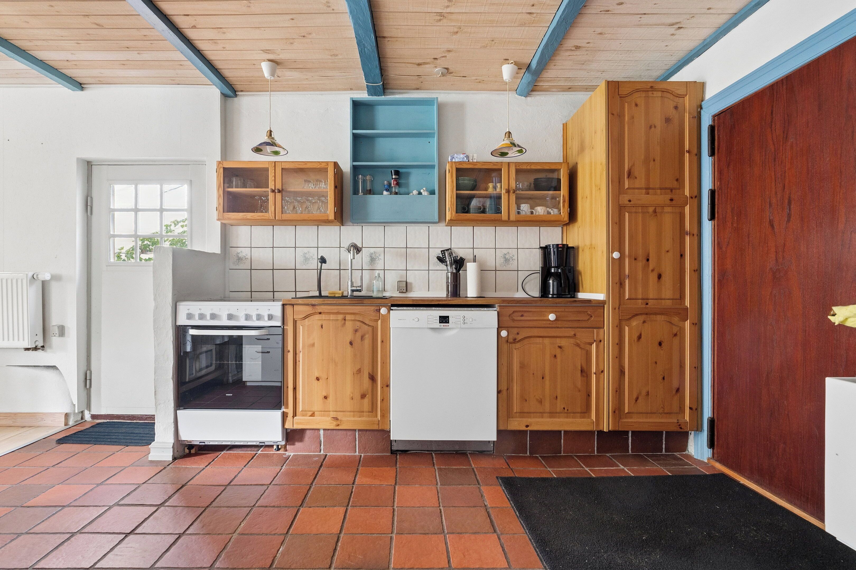 A kitchen with wooden cabinets, a white dishwasher, a stove, and a blue shelf.