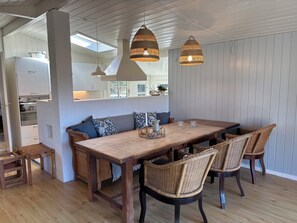 Un comedor con mesa de madera, sillas de mimbre e iluminación colgante.