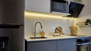 Una cocina moderna con un refrigerador de acero inoxidable, un lavamanos integrado y un microondas.