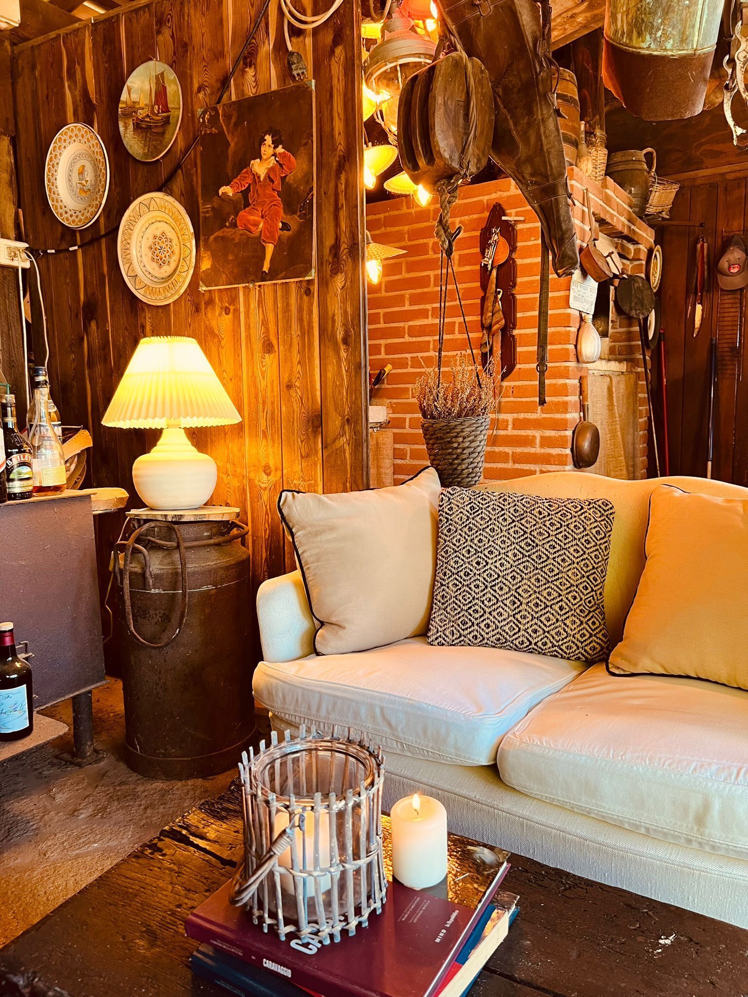 Una habitación acogedora con una pared de madera, un sofá blanco, una lámpara y diversos objetos decorativos.