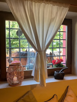 A window with a curtain, a woven basket with flowers, and a mortar and pestle on a windowsill.