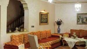 Un salon traditionnel avec un canapé, une table ornée d’un vase, un lustre et un escalier.