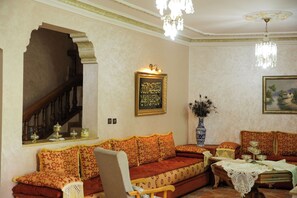 A traditional living room with a sofa, a table with a vase, a chandelier, and a staircase. - Luxurious, spacious, and family-friendly villa (Marina Smir)