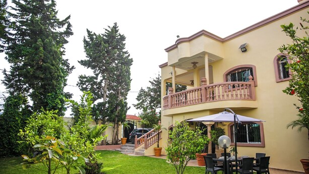 Un bâtiment à deux étages doté d’un balcon, d’un escalier et d’un patio aménagé avec du mobilier d’extérieur.