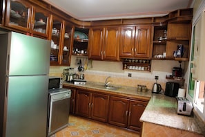 A kitchen with wooden cabinets, a refrigerator, a dishwasher, a sink, and a toaster.