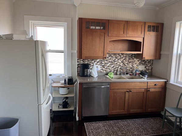 A kitchen with wooden cabinets, a stainless steel dishwasher, and a tiled backsplash.