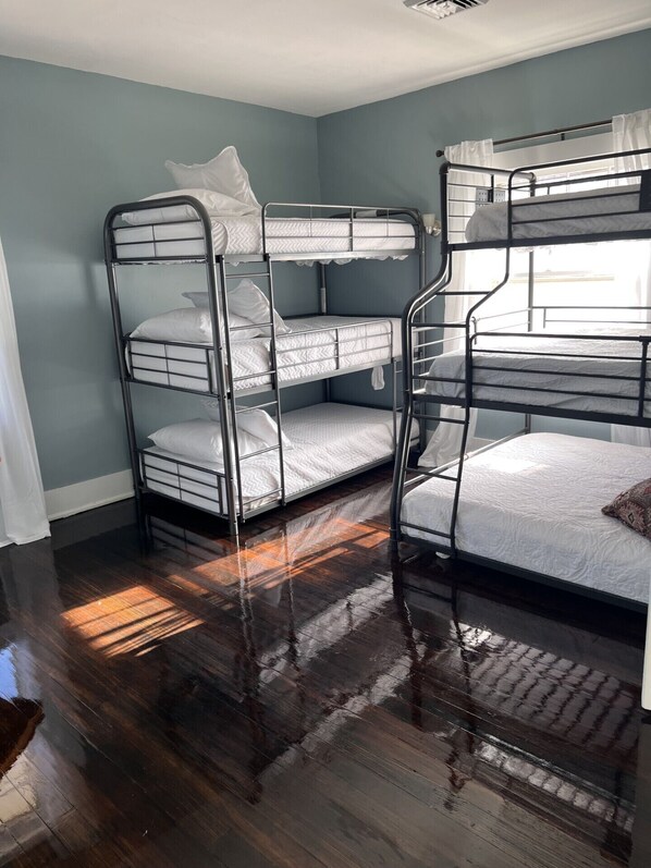 A bunk bed room with a wooden floor and a window with curtains.