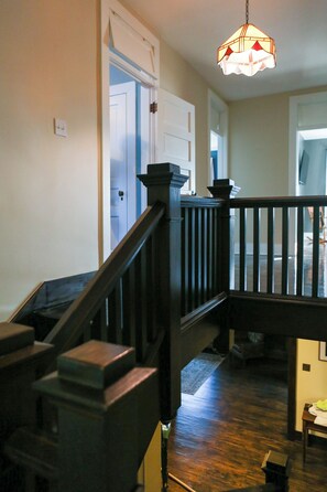 A wooden staircase with a dark finish, leading to a landing with a white door.