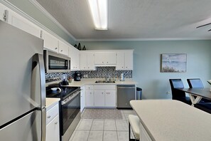 A modern kitchen with white cabinets, a stainless steel refrigerator, a microwave, and a dishwasher. - Poinciana Place #222 | Near Beach, Great Location, Resort Amenities (Miramar Beach)