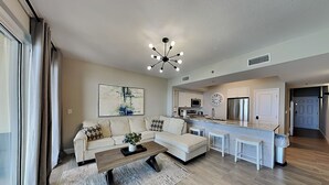 Une cuisine moderne avec un îlot central, un coin repas avec un canapé et un salon avec une table basse.