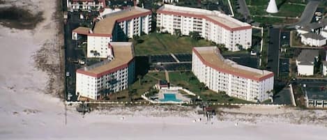 Um complexo hoteleiro à beira-mar, com vários edifícios, piscina e praia.