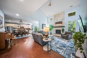 A spacious living area with a fireplace, a dining area with wooden furniture, and a kitchen with modern appliances. - Luxury Concord Retreat | Spacious Home with Hot Tub, Game Room, Pool Table, Fire Pit, Grill & More! (Concord)