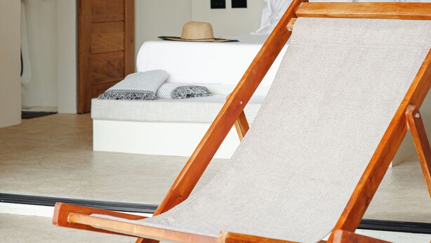 Une pièce comprenant un lit, une chaise en bois, un luminaire suspendu et une porte coulissante.
