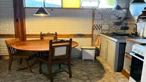 Una cucina con un tavolo da pranzo in legno, sedie, un frigorifero bianco e un piano cottura.