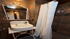 Un bagno con un lavandino bianco, uno specchio con cornice decorata e una tenda da doccia.