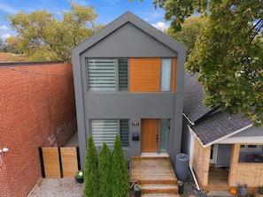 A modern two-story house with a grey facade, a wooden front door, and a visible number '707'.
