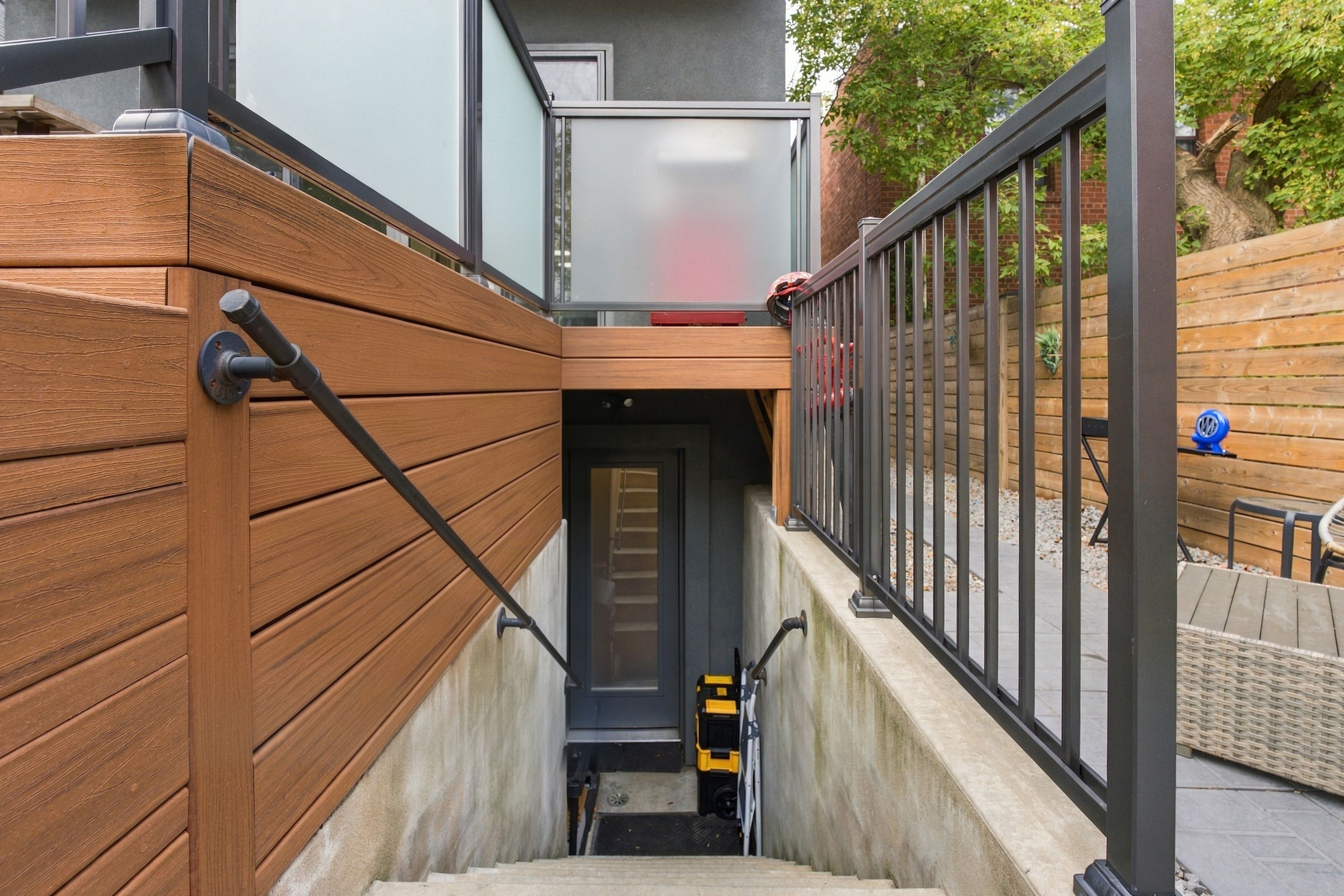 A staircase leading to a building entrance with a wooden handrail and metal railing.