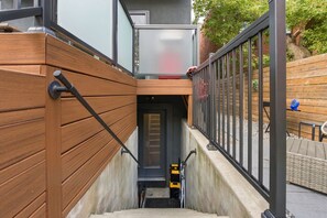 A staircase leading to a building entrance with a wooden handrail and metal railing.