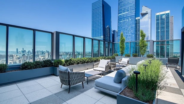A rooftop terrace with modern seating, a view of a city skyline, and tall buildings in the background. - Luxury 1BR, Skyline Views, Penn Station (New York)
