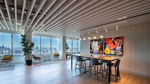 An office space with a city view, modern furniture, and a large abstract painting. - Luxury 1BR, Skyline Views, Penn Station (New York)
