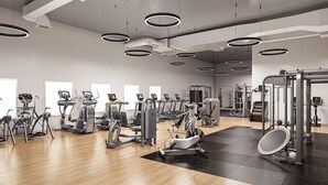 A gym with various exercise machines, a large mirror, and a black mat on the floor. - Luxury 1BR, Skyline Views, Penn Station (New York)