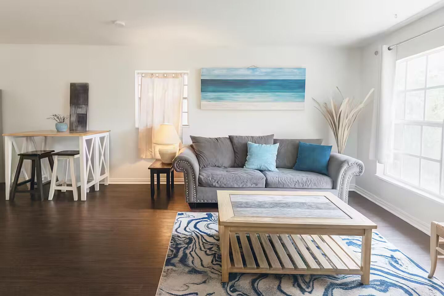 A living room with a grey sofa, wooden coffee table, and a painting of a beach.