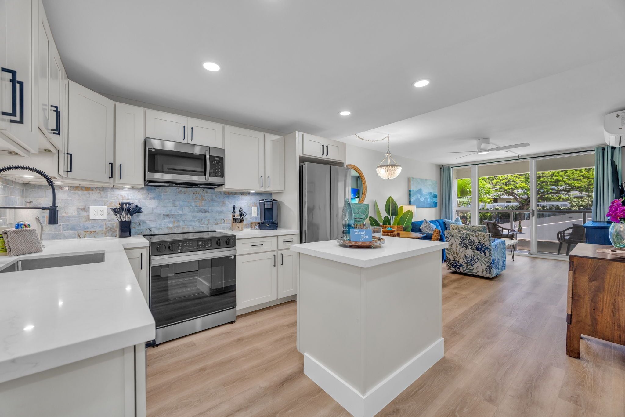 A modern kitchen with white cabinetry, stainless steel appliances, and a central island.