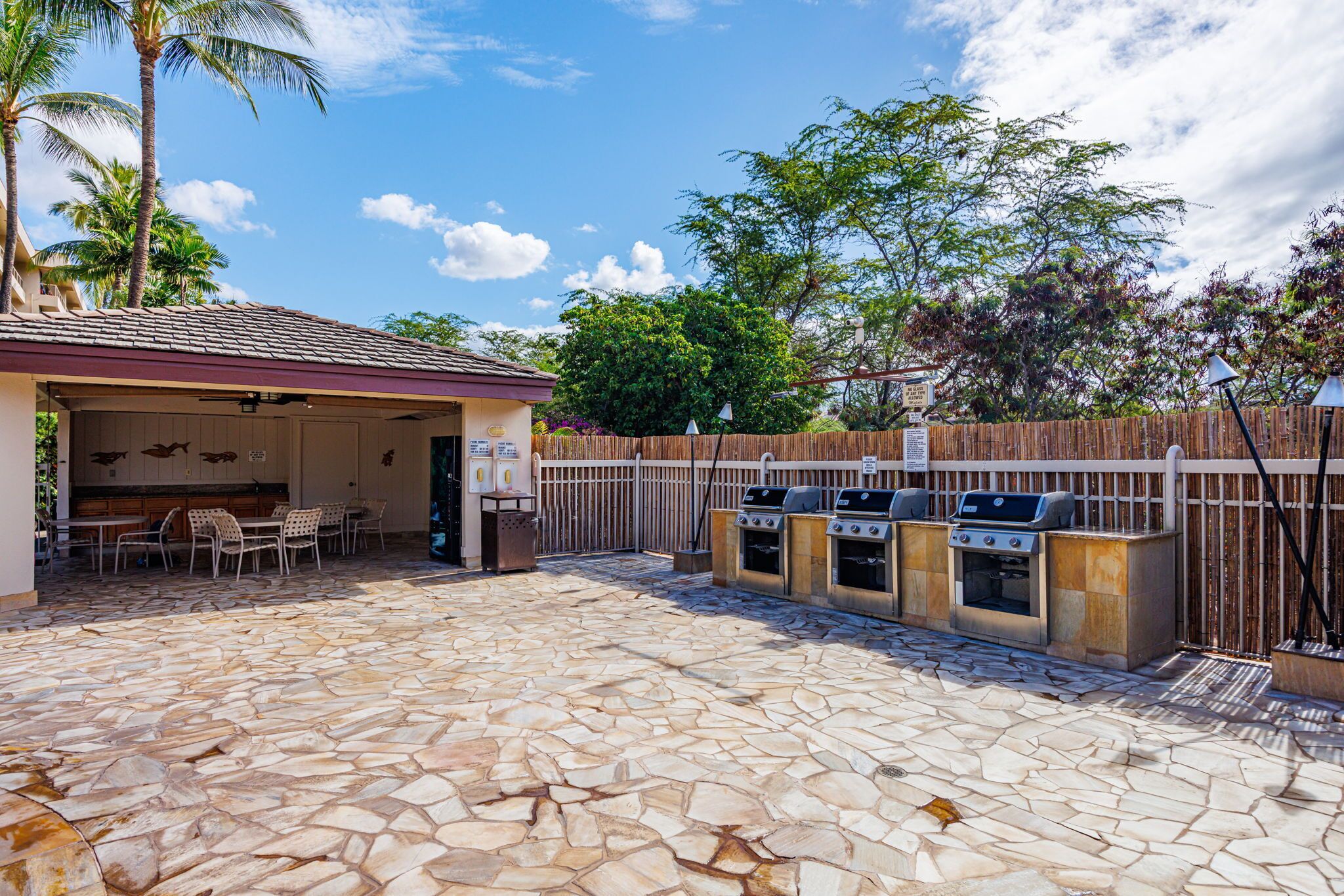 Un patio al aire libre con suelo de piedra, una zona de estar cubierta y una parrilla para barbacoa.
