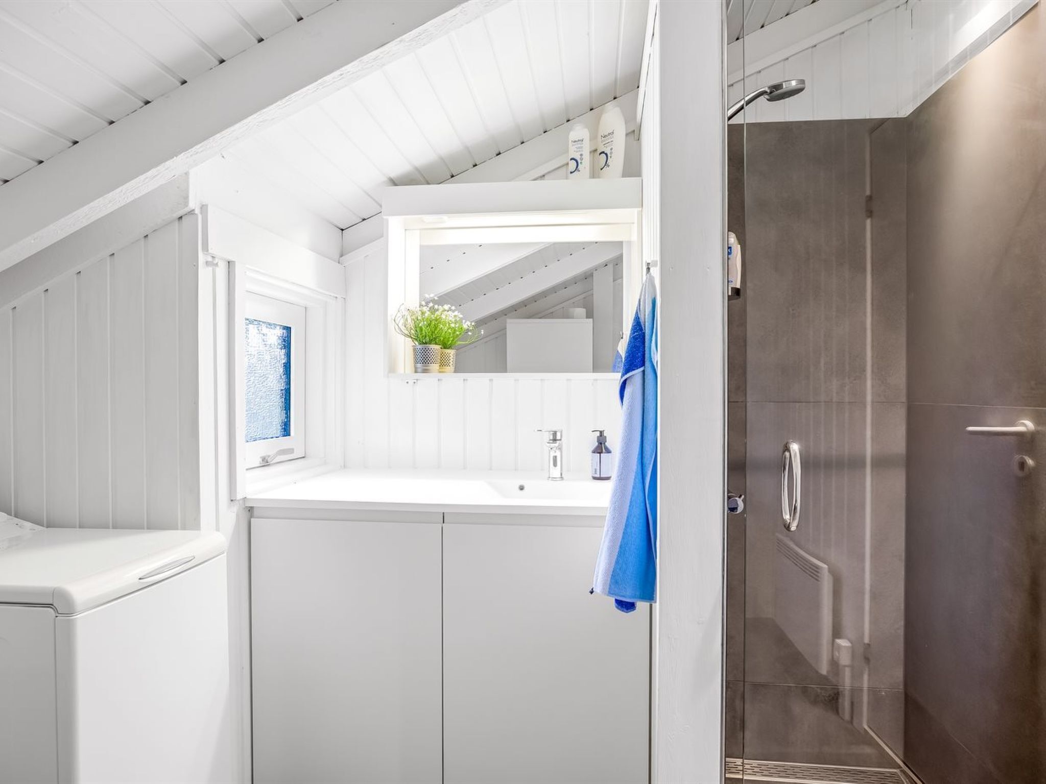 A modern bathroom with a shower, a sink, and a mirror.