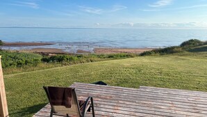Una terrazza con una sedia, un prato e vista sul mare.