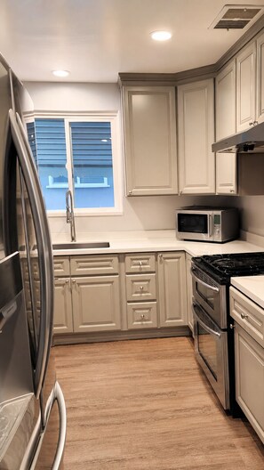 A kitchen with a refrigerator, microwave, stove, and cabinets. - Urban Oasis: Private 2BR + Lush Backyard in LA (Los Angeles)