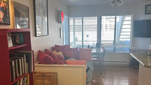Ein Wohnzimmer mit einer Couch, einem Bücherregal, einem Deckenventilator und einem Fenster mit Jalousien.