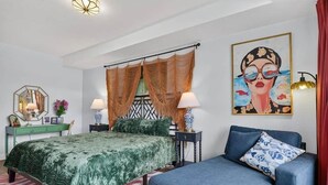 Ein Schlafzimmer mit einem Bett, einem Sofa, einem Gemälde und einer Lampe.