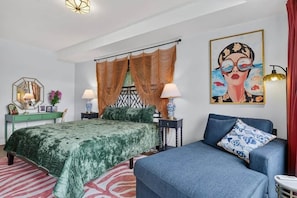 Un dormitorio con una cama, un sofá, un cuadro y una lámpara.