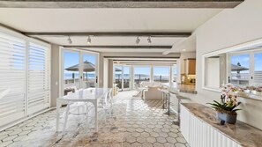 Ein geräumiger Balkon mit Blick auf den Ozean, eine Essecke mit Glastisch und eine Küchenzeile.