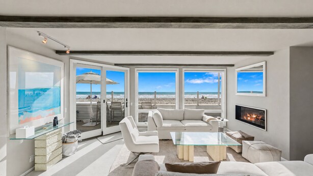 A modern living room with a glass coffee table, white sofas, and a fireplace.