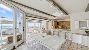 A modern kitchen with a large island, bar stools, and a view of the beach.
