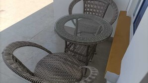 Un balcon agrémenté de meubles en osier, notamment une table ronde et deux chaises.