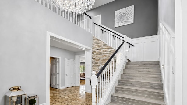 A staircase with white balusters and a wooden finish, leading to a landing with a chandelier. - 4BR w putting green, gym, outdoor kitchen (Queen Creek)