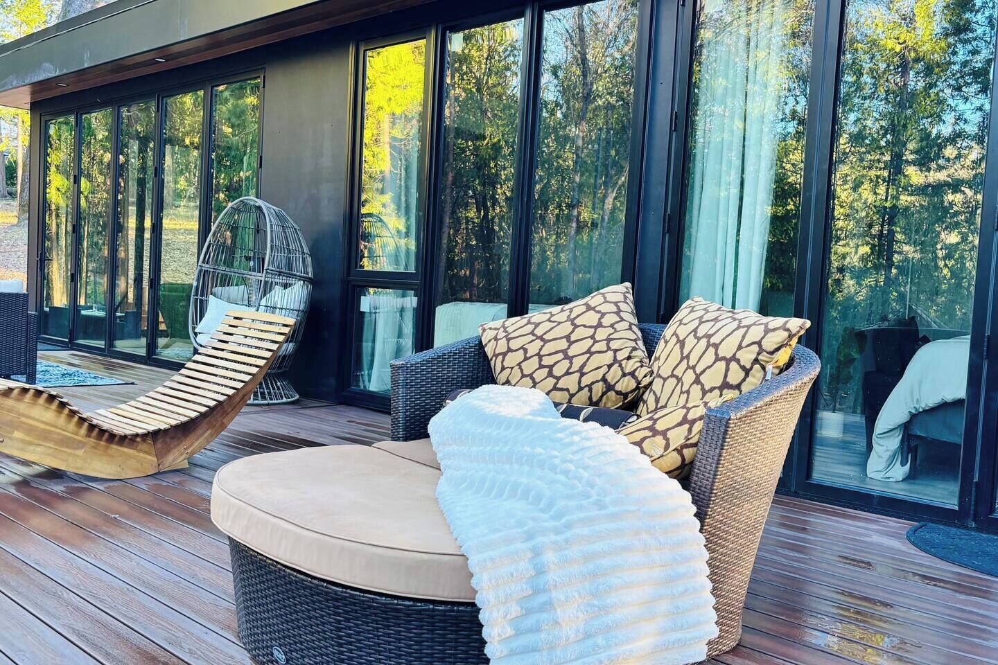 Une terrasse dotée de meubles en osier, notamment une chaise et un canapé avec des coussins à motifs.