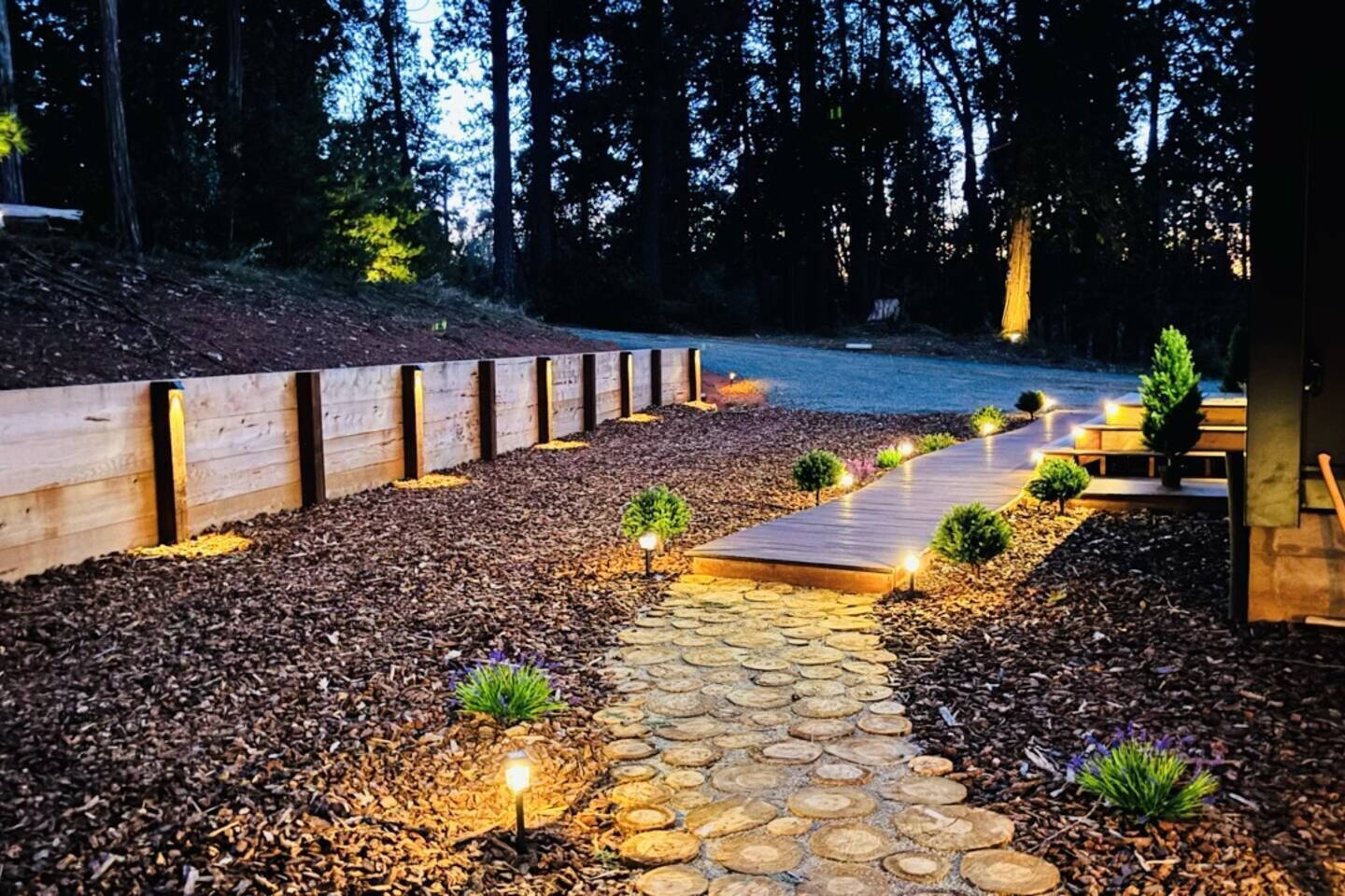 A stone pathway leading to a wooden deck surrounded by a forest.