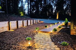 A stone pathway leading to a wooden deck surrounded by a forest.