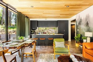 Una cocina moderna con armarios oscuros, una isla central y un comedor con mesa dispuesta para cuatro.
