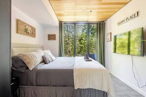 Ein Schlafzimmer mit einem Bett, einem Fernseher, einem Fenster mit Vorhängen und einem Schild mit der Aufschrift 'HAPPY PLACE'.