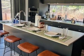 Una cocina moderna con una isla central, taburetes de bar y una barra para café.