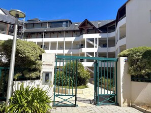 Ein mehrstöckiges Gebäude mit geschlossenem Eingangsbereich und einer Treppe vor blauem Himmel.