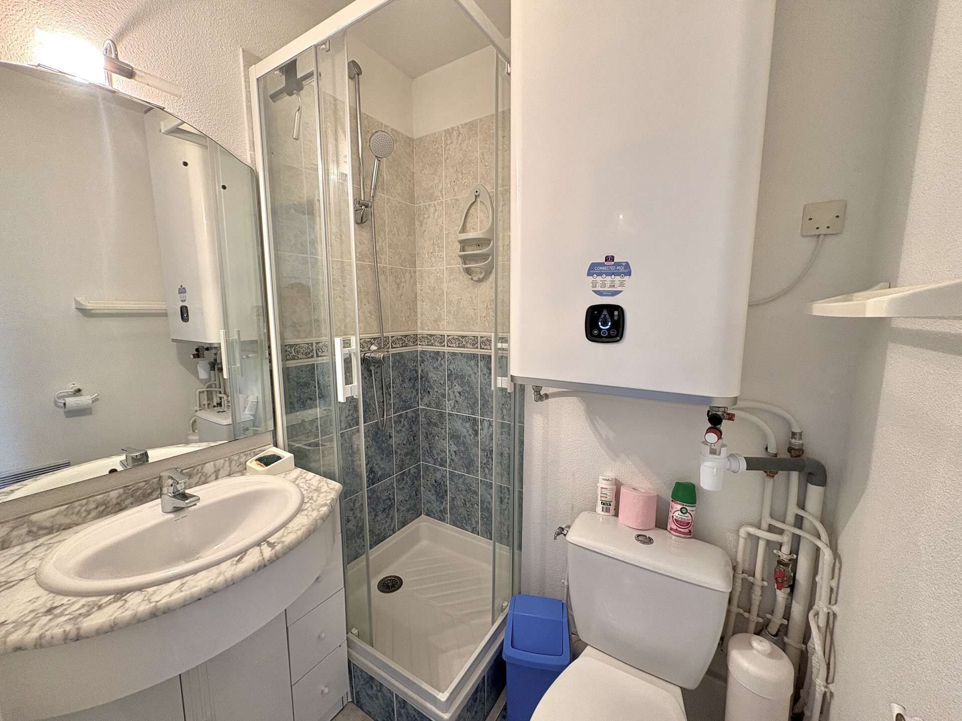Une salle de bain équipée d’une douche, de toilettes, d’un lavabo et d’un miroir.